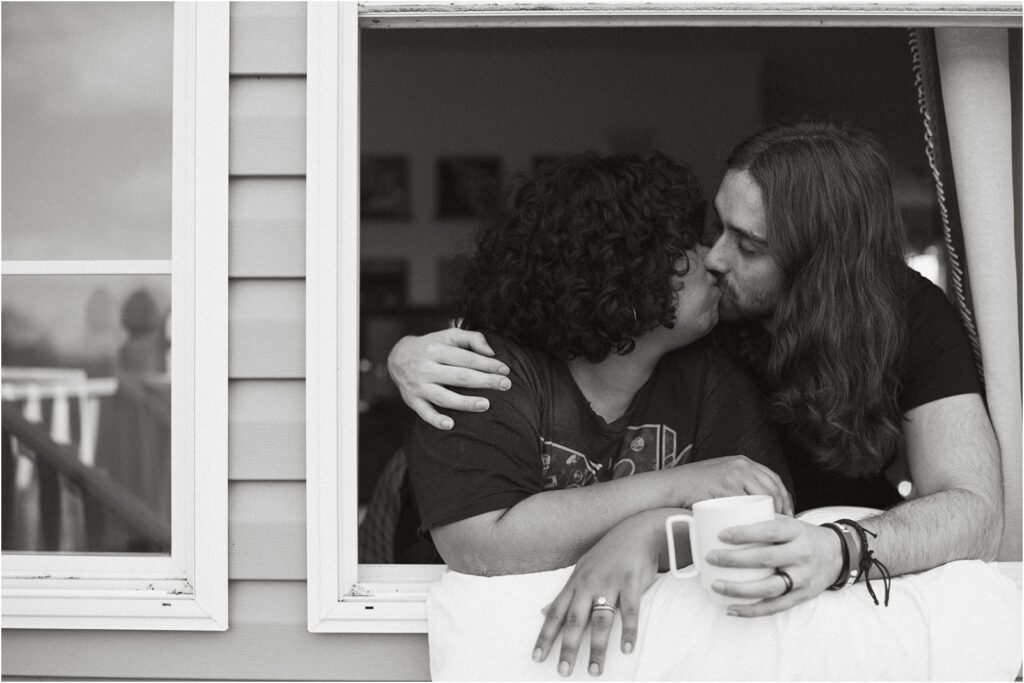Couple kissing in window holding cup of coffee.